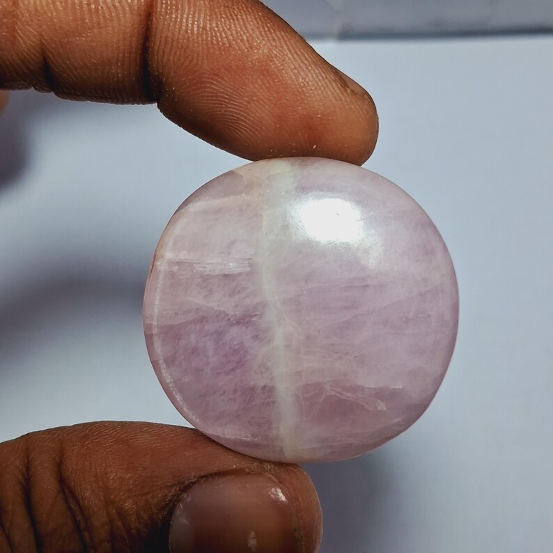 Op de afbeelding: Een ronde, gepolijste roze en witte edelsteen met een glad, glanzend oppervlak.