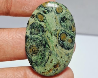 May include: Oval shaped green and brown ocean jasper cabochon with a swirling pattern.
