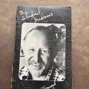 May include: A black and white photo of a man with a mustache on the cover of a book titled "A Studied Madness" with the author's signature "Heywood Hale Brown" underneath the photo.