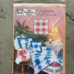 May include: A vintage sewing pattern for a Fleur-de-lis quilt, wall hanging, or pillows. The pattern is from That Patchwork Place, Inc. and features a country French flair. The pattern includes instructions for machine applique, hand applique, or stenciling.