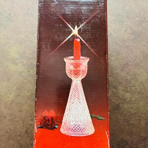 May include: A clear glass candle holder with a diamond pattern. The holder is on a red background with a red rose.