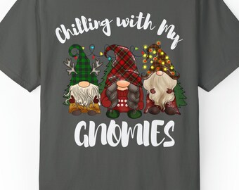 May include: A dark grey t-shirt with the text "Chilling with my Gnomies" in white. Three gnomes are depicted wearing Christmas-themed hats and holding lights.