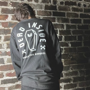 May include: Black long-sleeve shirt with a white graphic of a coffin with the text "Dead Inside" and "Monster Apparel" on the back.