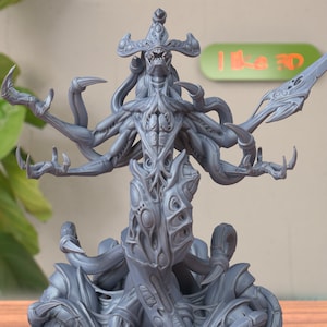 Può includere: Miniatura stampata in 3D di colore grigio di una creatura con più braccia e tentacoli con una testa a forma di corona. La creatura ha un design organico dettagliato con più occhi e una bocca spalancata.