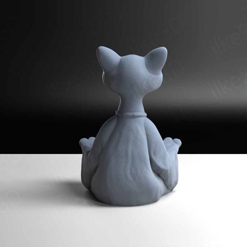 Op de afbeelding: Een grijs keramiek kattenbeeldje dat in een meditatieve yogapose zit met gekruiste benen en handen in mudra-positie.