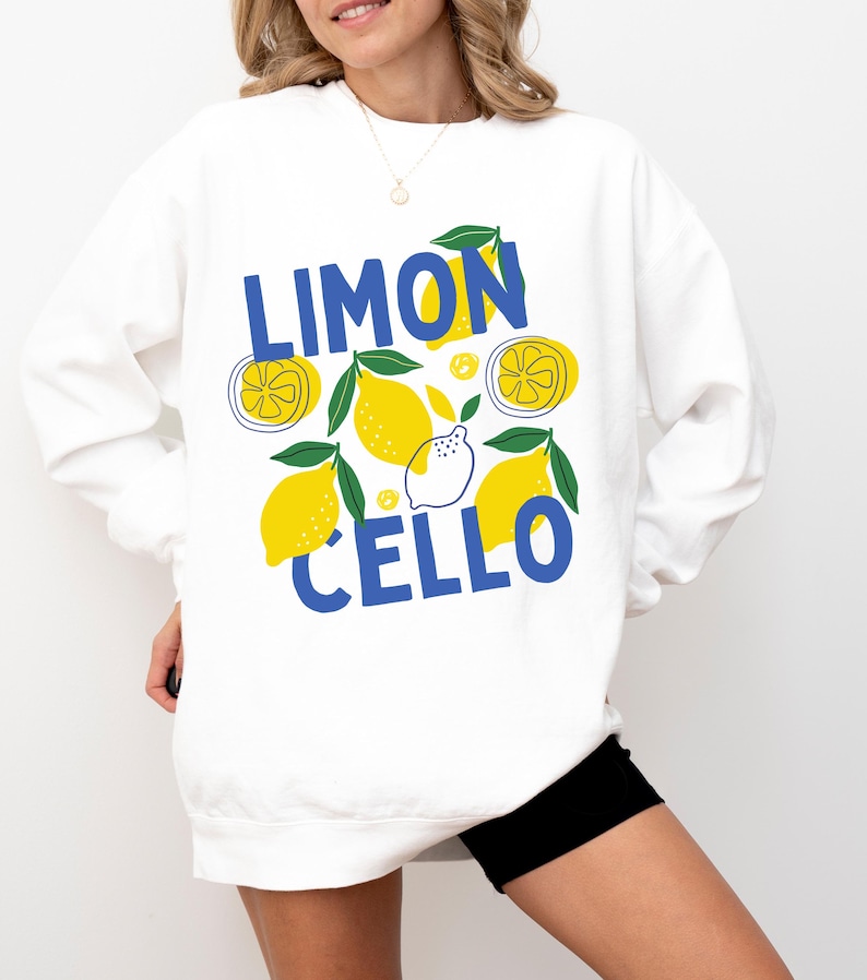 May include: White sweatshirt with a blue and yellow graphic design featuring lemons and the text "LIMONCELLO".