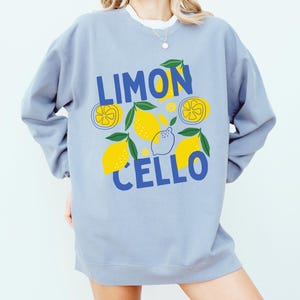 May include: A light blue sweatshirt with a graphic design of lemons and the text "LIMONCELLO" in blue.