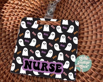May include: A black and white ghost pattern ID badge holder with the word "NURSE" in purple and white letters. The holder is attached to a clear retractable badge reel.