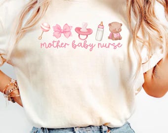 May include: A white t-shirt with the text "mother baby nurse" and pink baby icons, including a rattle, bow, pacifier, bottle, and teddy bear. The shirt is on a model wearing blue jeans.
