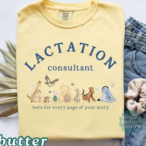 May include: A pale yellow t-shirt featuring the dark blue text LACTATION consultant and the phrase here for every page of your story. The design includes illustrations of Winnie the Pooh characters including Kanga, Roo, Piglet, Pooh, Rabbit, Tigger, and Eeyore.