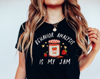 May include: Black t-shirt with the text "Behavior Analysis is my jam" in white. A cartoon jar of strawberry jam with stars and strawberries is above the text.