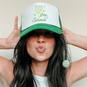 May include: A white and green trucker hat with the text "Tequila Lime and Sunshine" and a green lime margarita illustration.