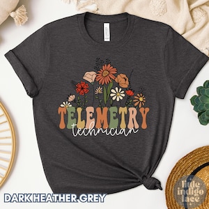 May include: Dark heather grey t-shirt with a floral design and the text "Telemetry technician".