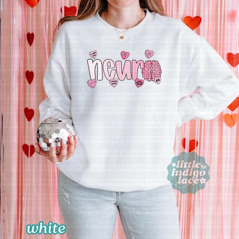 May include: White sweatshirt with the word "neuro" in a pink gingham font, a pink brain graphic, and pink heart-shaped candies with phrases like "I love you" and "neuro crew." The sweatshirt has long sleeves.