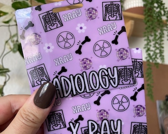 May include: Purple badge with a repeating pattern of skeletons, radiation symbols, disco balls, and flowers. The text "RADIOLOGY" and "X-RAY" are printed in white on the badge.