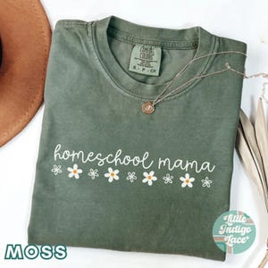 May include: A green t-shirt with the text "homeschool mama" in white lettering and a row of white daisies with yellow centers. The shirt has a tag that says "Comfort Colors" and "S-P-CH".