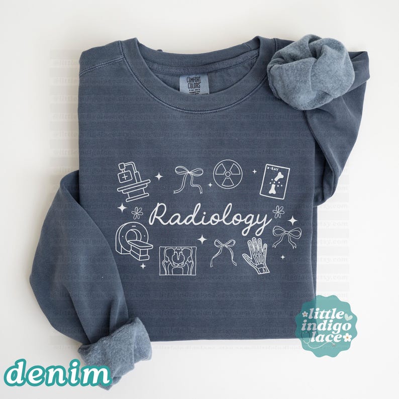 May include: Denim blue sweatshirt with white "Radiology" text and related medical illustrations. Features a crew neck and long sleeves, with the word "denim" at the bottom left. The sweatshirt has a relaxed fit and a soft, comfortable appearance.
