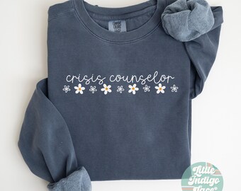 May include: A dark blue sweatshirt with the text "crisis counselor" in white lettering and a row of white daisies below.