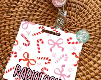 Könnte beinhalten: Weißer Badgehalter mit einem Muster aus roten und rosa Zuckerstangen und Schleifen. Der Text "RADIOLOGY" ist in rosa Buchstaben geschrieben.