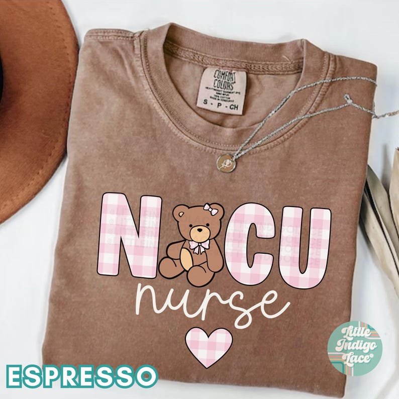Puede incluir: Una camiseta marr&oacute;n con el texto "NICU nurse" en letras de cuadros rosas y blancos. Un coraz&oacute;n de cuadros rosas y blancos est&aacute; debajo del texto. Un oso de peluche marr&oacute;n con un lazo rosa est&aacute; en el medio del texto. El texto "ESPRESSO" est&aacute; en la parte inferior de la camiseta.