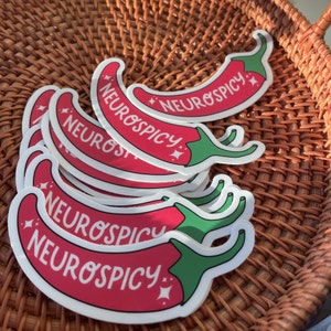 May include: A stack of red and green chili pepper stickers with the text "Neurospicy" on each one.