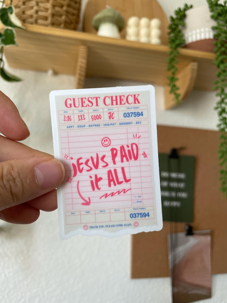May include: A pink and white sticker with a receipt design. The sticker says "JESUS PAID it ALL" in red lettering. The sticker has a check mark and a smiley face.