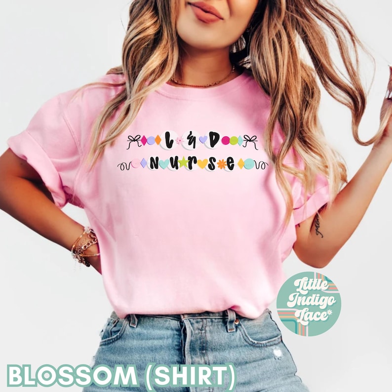 K&ouml;nnte beinhalten: Rosa T-Shirt mit dem Text "I  <3  DOGS  NURSE" in schwarzen Buchstaben mit bunten Verzierungen.
