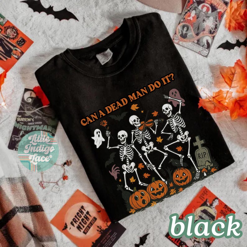 May include: Black t-shirt with a Halloween-themed graphic. The design features dancing skeletons, pumpkins, ghosts, and the text "CAN A DEAD MAN DO IT?". The word "black" is printed at the bottom right.