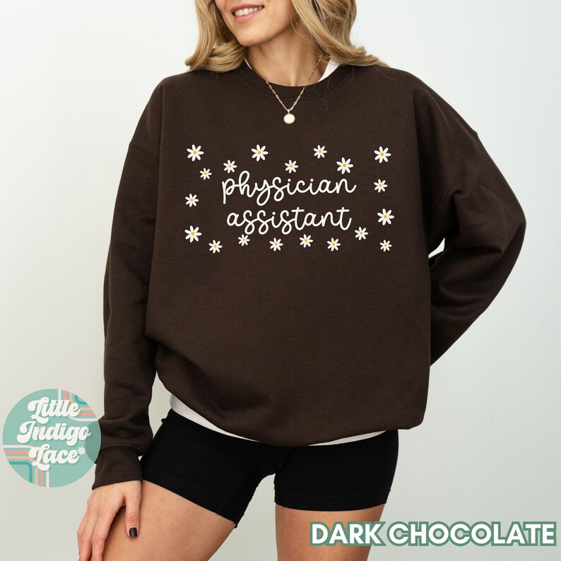 May include: A dark chocolate brown sweatshirt with the text "physician assistant" in white lettering surrounded by white daisy flowers.
