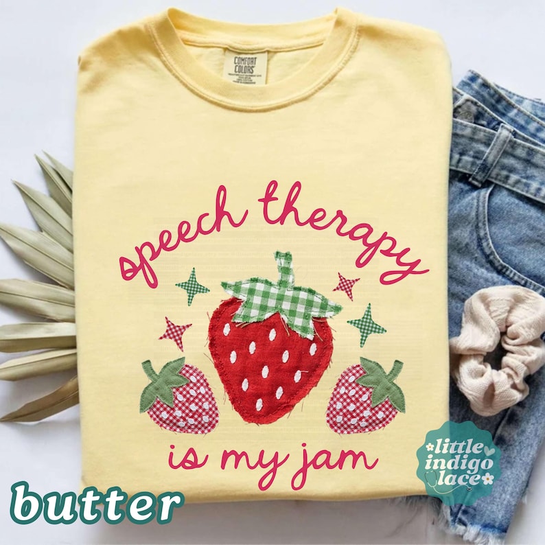 K&ouml;nnte beinhalten: Hellgelbes T-Shirt mit dem Schriftzug "speech therapy is my jam" in rosa Schrift. Das Design umfasst eine gro&szlig;e Erdbeere mit einem gr&uuml;n-wei&szlig; karierten Oberteil und zwei kleineren Erdbeeren. Gr&uuml;ne und rosa Sterne sind ebenfalls vorhanden.