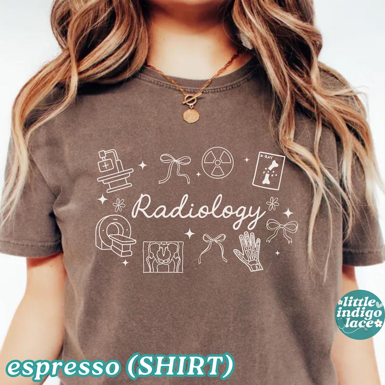 May include: Espresso-colored t-shirt with white Radiology-themed graphics. The design includes medical equipment, anatomical illustrations, and the word "Radiology" in a decorative font. The shirt has a crew neck and short sleeves.