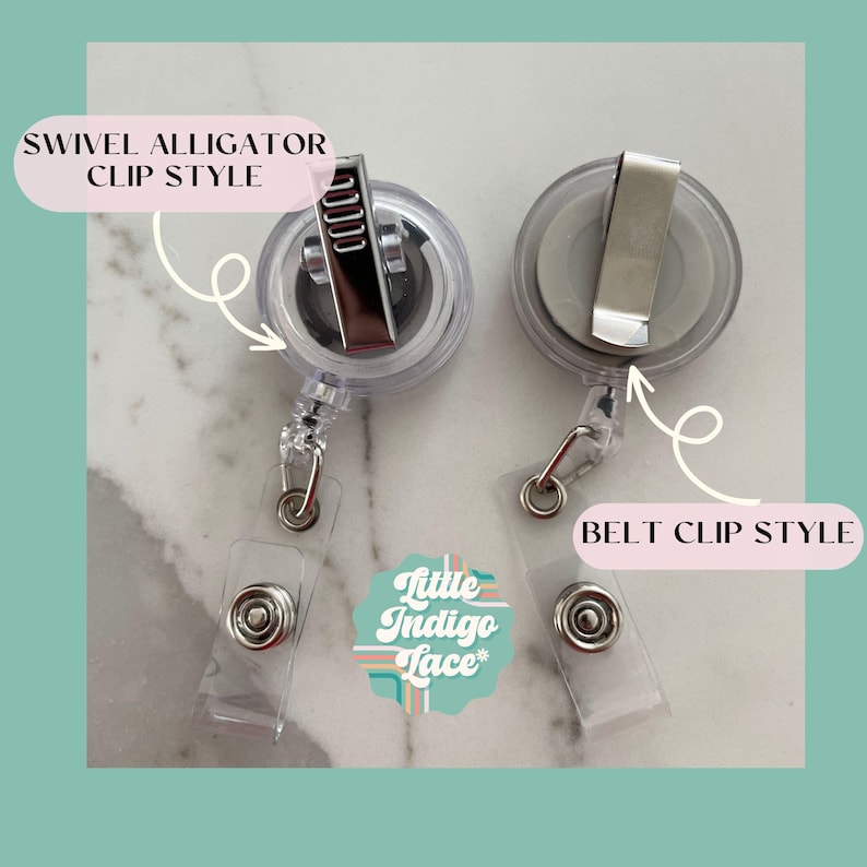 May include: Two clear badge reels with different clip styles. One has a swivel alligator clip, and the other has a belt clip. The reels have a clear plastic body with a retractable cord and a clear plastic snap. The text "Little Indigo Lace" is also visible.
