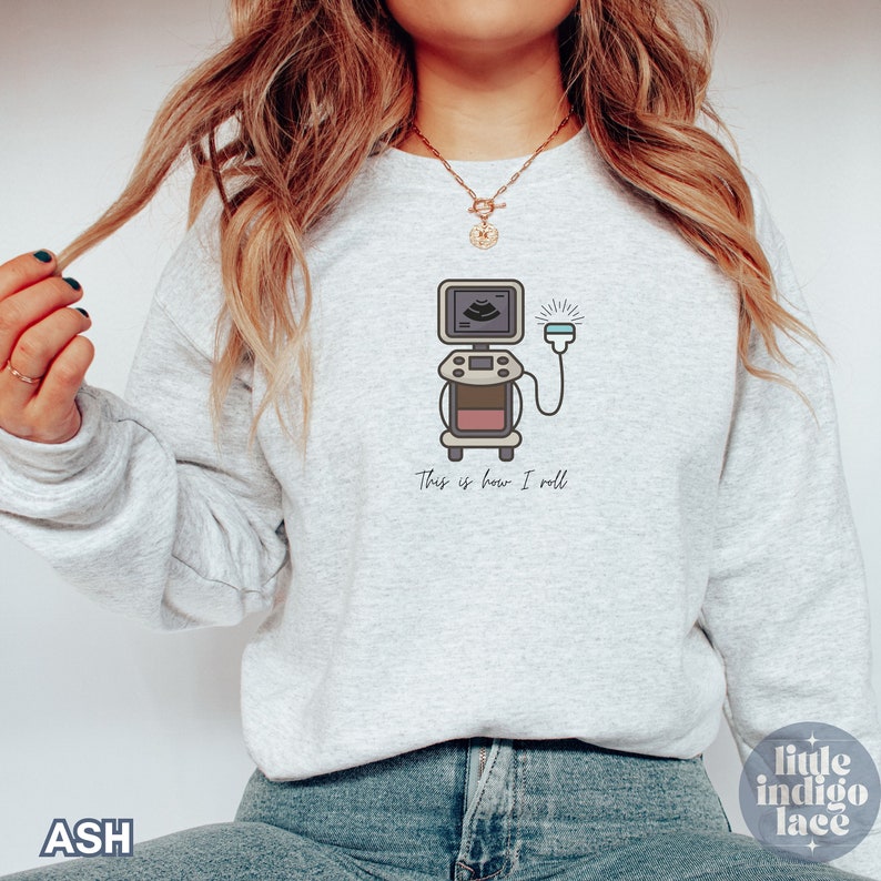 May include: Ash-colored sweatshirt featuring a medical ultrasound machine graphic. The design includes the text "This is how I roll" below the machine. The sweatshirt is a light gray color.