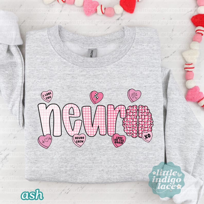 May include: A light gray sweatshirt with the word "neur" in a pink gingham pattern, a pink brain graphic, and several pink heart-shaped candies. The candies have phrases like "I Lobe You" and "Love on the Brain".