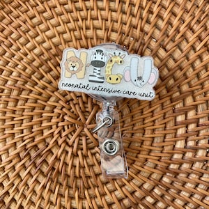 May include: A clear badge reel with a decorative top featuring the letters NICU, each letter designed with a different animal: a lion, zebra, giraffe, and elephant. The words "neonatal intensive care unit" are below the letters.