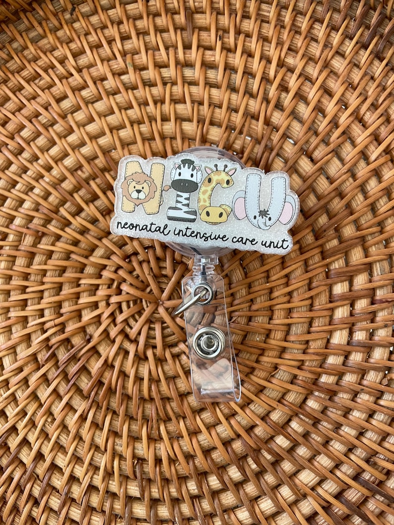 May include: A clear badge reel with a decorative top featuring the letters NICU, each letter designed with a different animal: a lion, zebra, giraffe, and elephant. The words "neonatal intensive care unit" are below the letters.