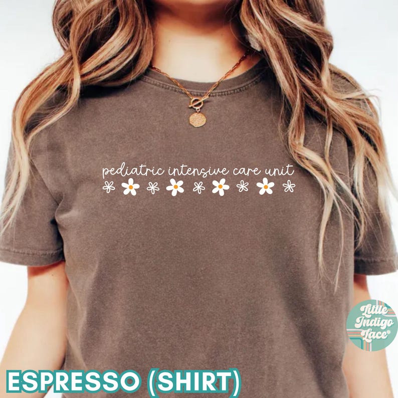 K&ouml;nnte beinhalten: Espresso-braunes T-Shirt mit dem Text "pediatric intensive care unit" und einer Reihe wei&szlig;er G&auml;nsebl&uuml;mchen.