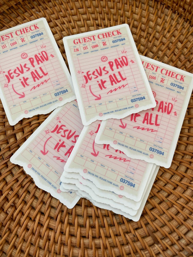 May include: A stack of stickers with a white background and pink and blue text. The text on the stickers reads "Jesus Paid it All".