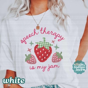 K&ouml;nnte beinhalten: Wei&szlig;es T-Shirt mit dem Text "speech therapy is my jam" in rosa Schrift. Das Design zeigt eine gro&szlig;e rote Erdbeere mit einem gr&uuml;nen Vichy-Oberteil und zwei kleineren Erdbeeren. Gr&uuml;ne und rosa Sterne erg&auml;nzen das Design.