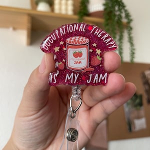May include: Pink glitter badge holder with a red and white jar of strawberry jam with the text "Occupational Therapy is my jam".
