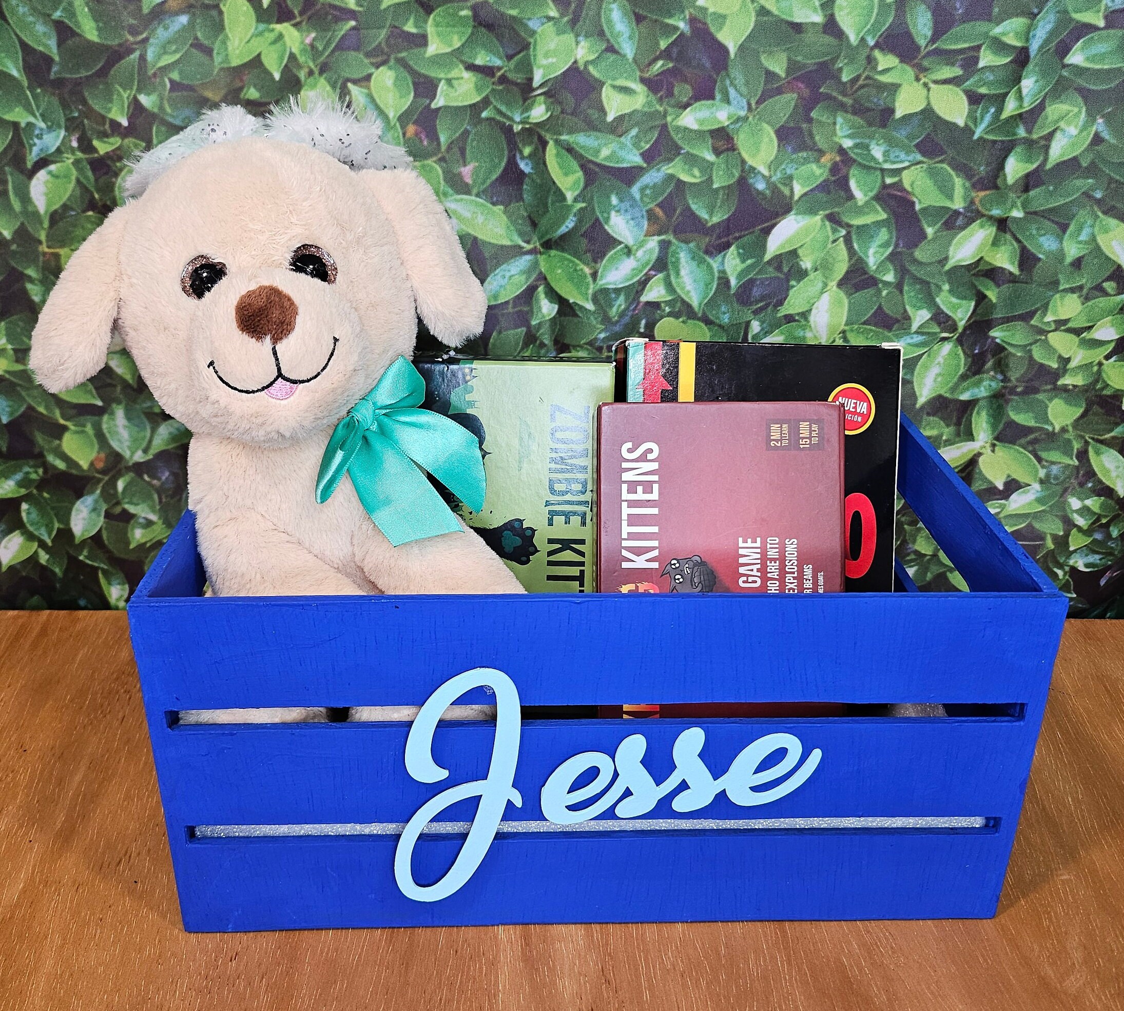 A blue wooden crate with light blue name. Ideal for organizing board games or adding a decorative touch to a nursery or kids room.