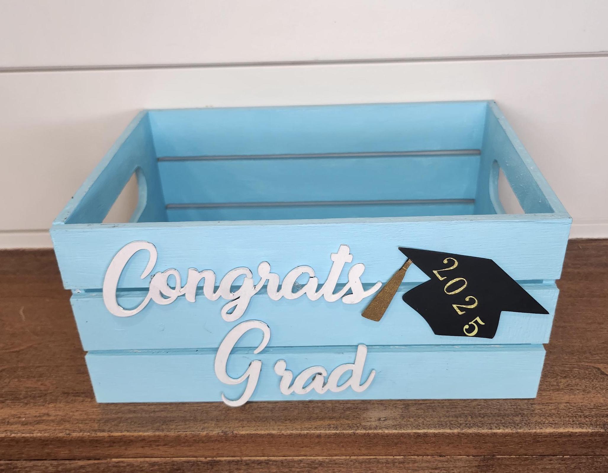 Custom light blue wooden graduation crate with a white name and a grad cap design featuring the graduation year. Perfect for holding gifts, cards, or as decor at graduation parties.