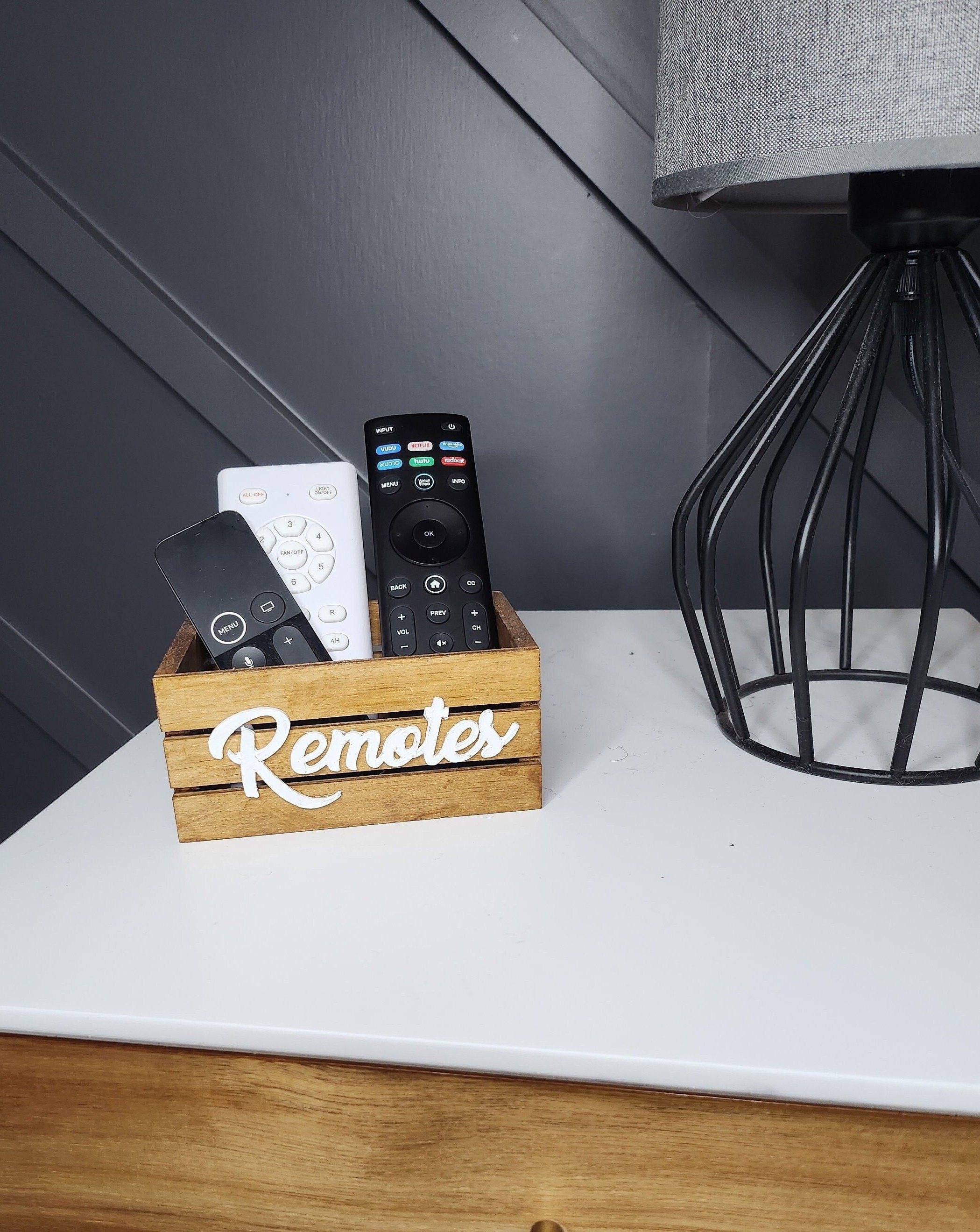 Stained wooden mini crate with a white Remotes word. The crate is perfect for farmhouse or modern decor. Ideal for home organization or decorative accents.