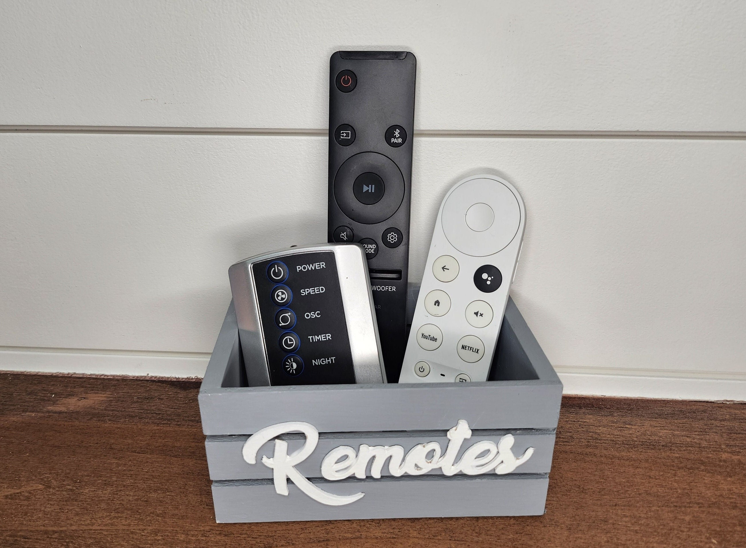 Grey wooden mini crate with a white Remotes word. The crate is perfect for farmhouse or modern decor. Ideal for remote controls organization and decorative accents.