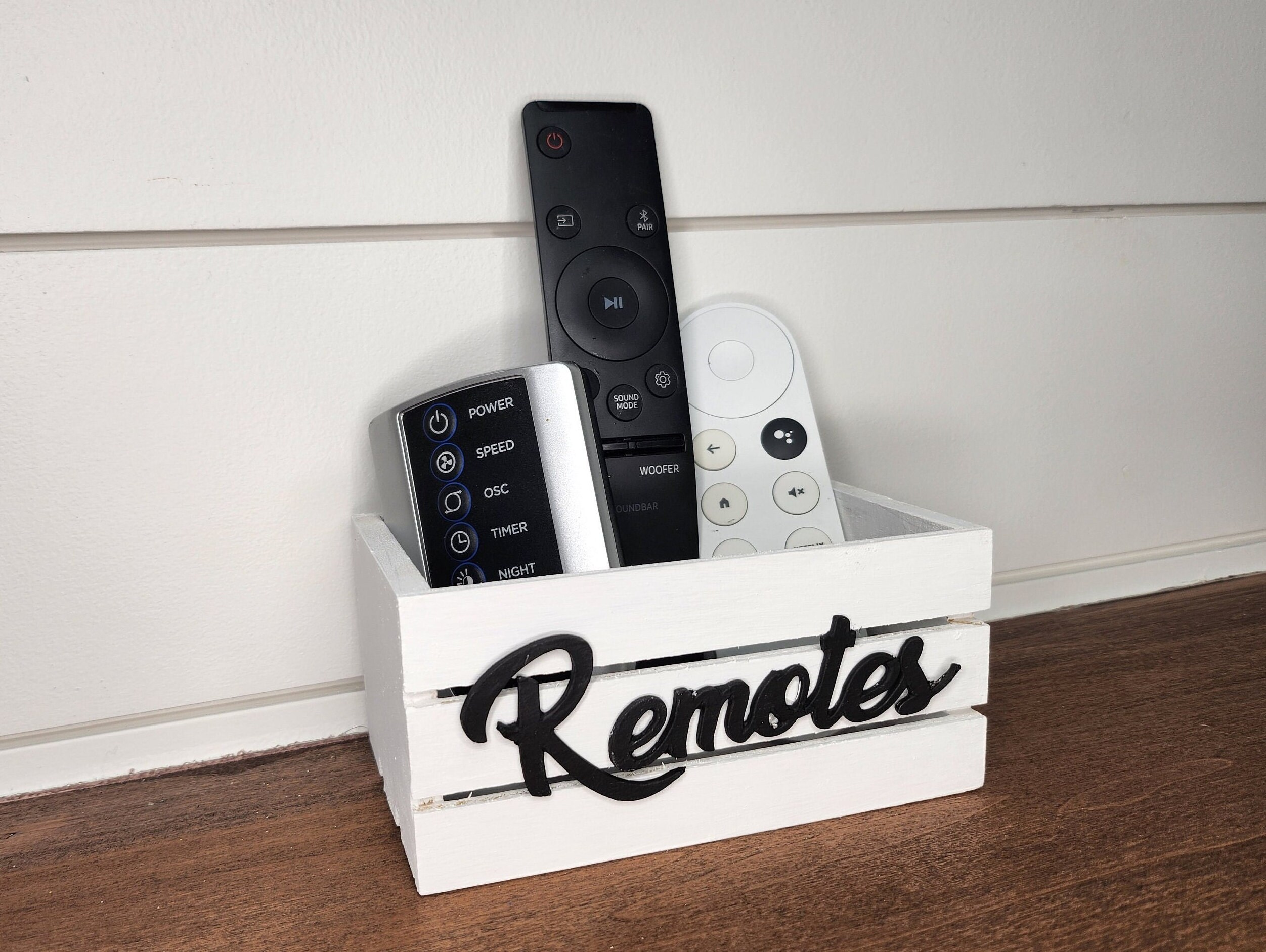 White wooden mini crate with a black Remotes word. The crate is perfect for farmhouse or modern decor. Ideal for remote controls organization and decorative accents.