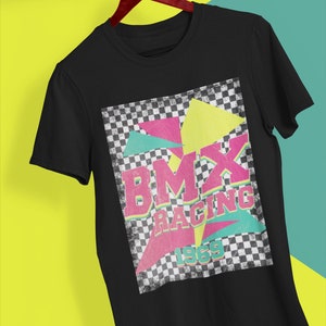 May include: Black t-shirt with a graphic print of a checkered background with colorful geometric shapes and the text "BMX RACING 1969".