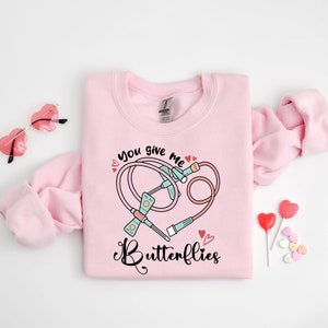 May include: Pink sweatshirt with a graphic of a stethoscope and the text "You give me butterflies".