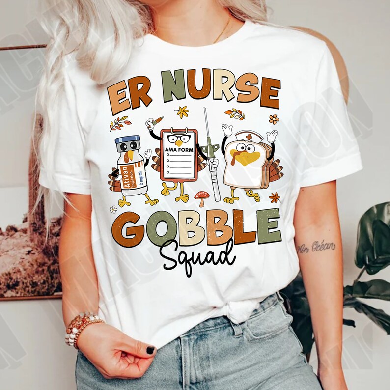 May include: White t-shirt with a Thanksgiving-themed design featuring turkeys dressed as nurses. The text reads "ER Nurse Gobble Squad".