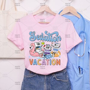 pink shirt illustrating a quirky medical relaxation scene with 'Sedation Vacation' text and personified sedative bottles and a pill.