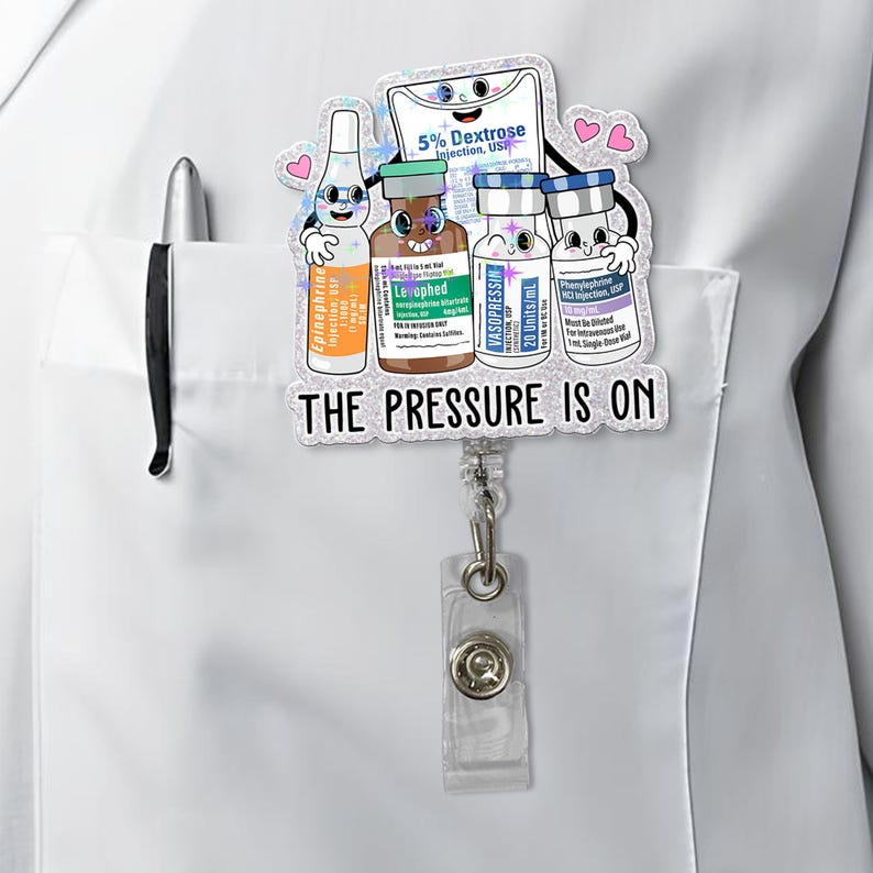 May include: A badge reel featuring cartoon illustrations of medical vials and a bag of dextrose. The text "THE PRESSURE IS ON" is displayed below the illustrations. The reel is attached to a white pocket.